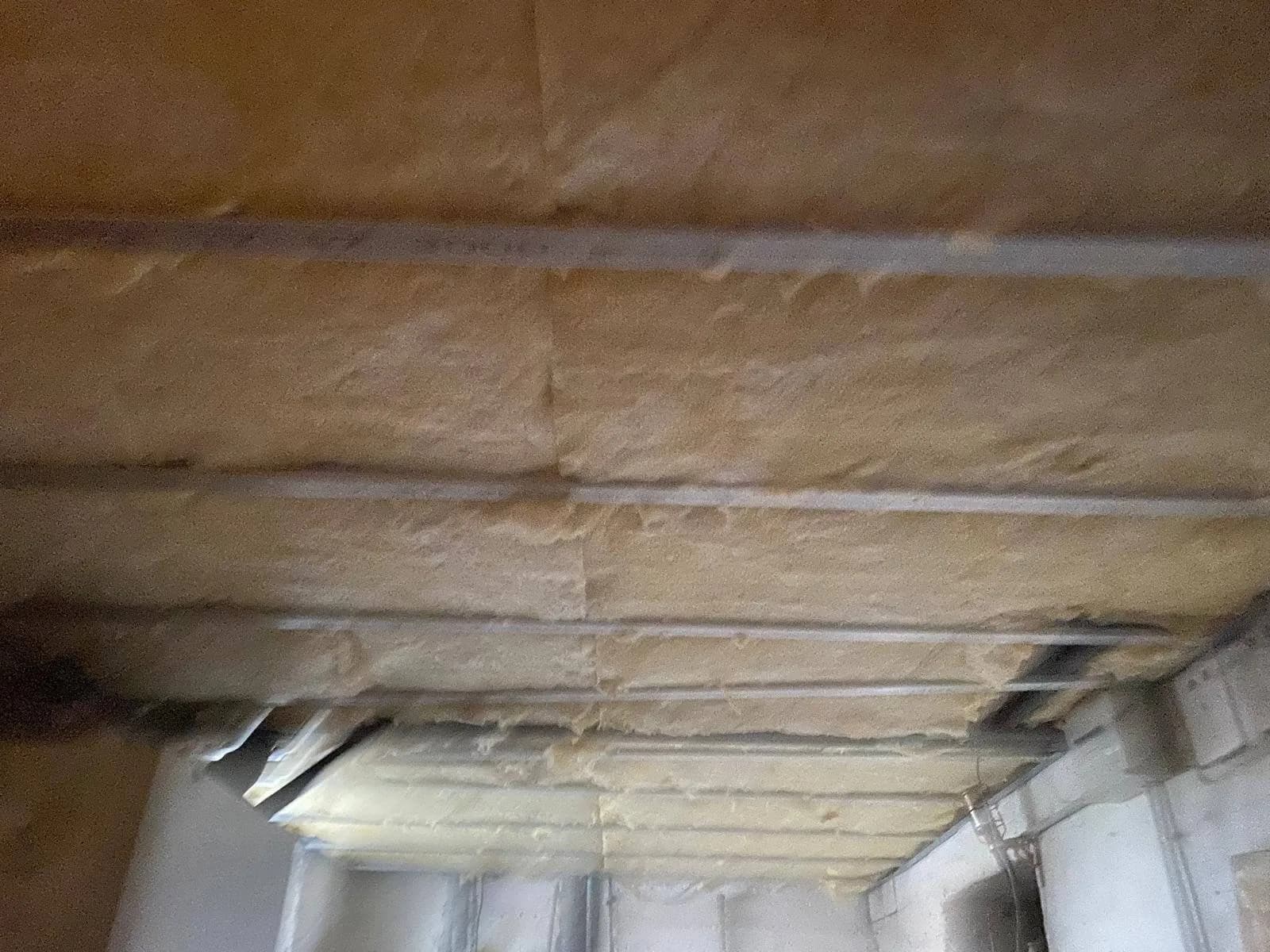 Laine isolante maintenue par des rails métalliques sous un plafond