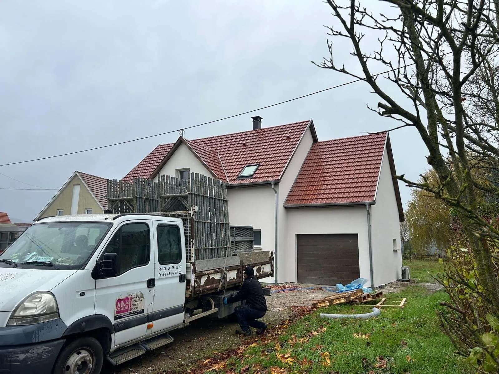 Camion de chantier AKS Bâtiment devant une maison neuve couverte en tuiles